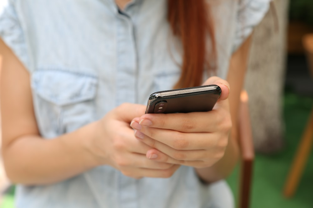 A person with red hair using an iPhone