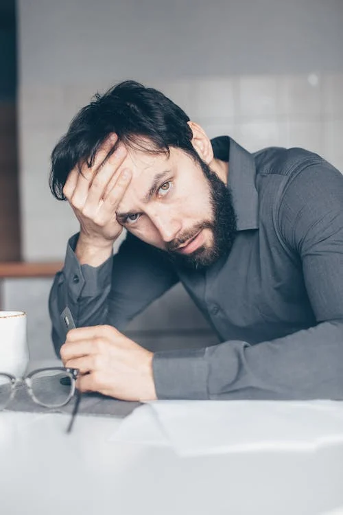 A man looking stressed holding his forehead