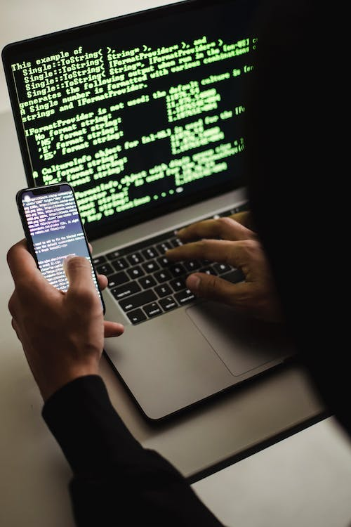 A person using a laptop and a phone at the same time