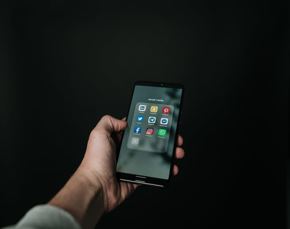 person holding a phone with social media app menu on the screen