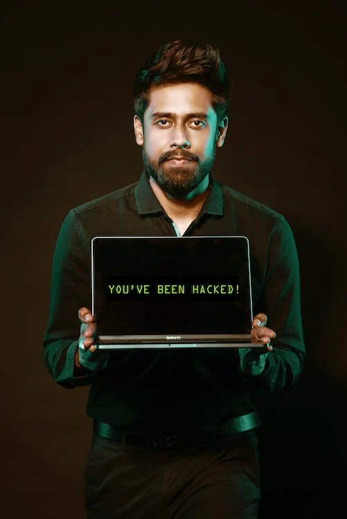 A man holding a laptop that has been hacked by cyberstalkers