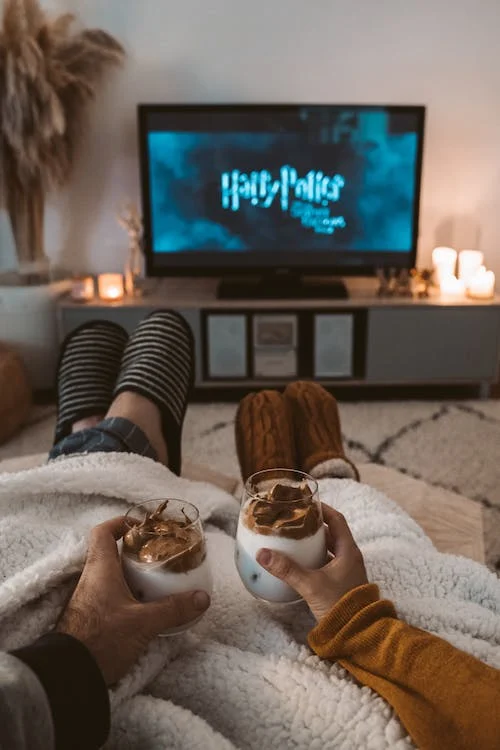 Two people watching Harry Potter while enjoying drinks