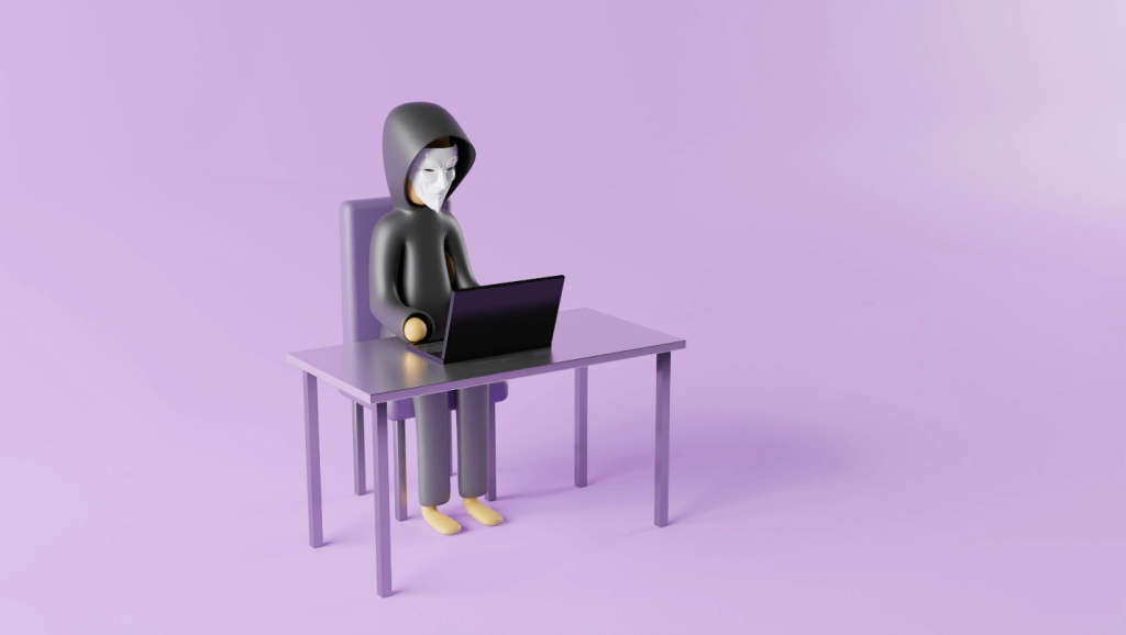 A figure using a laptop wearing a mask and a hood