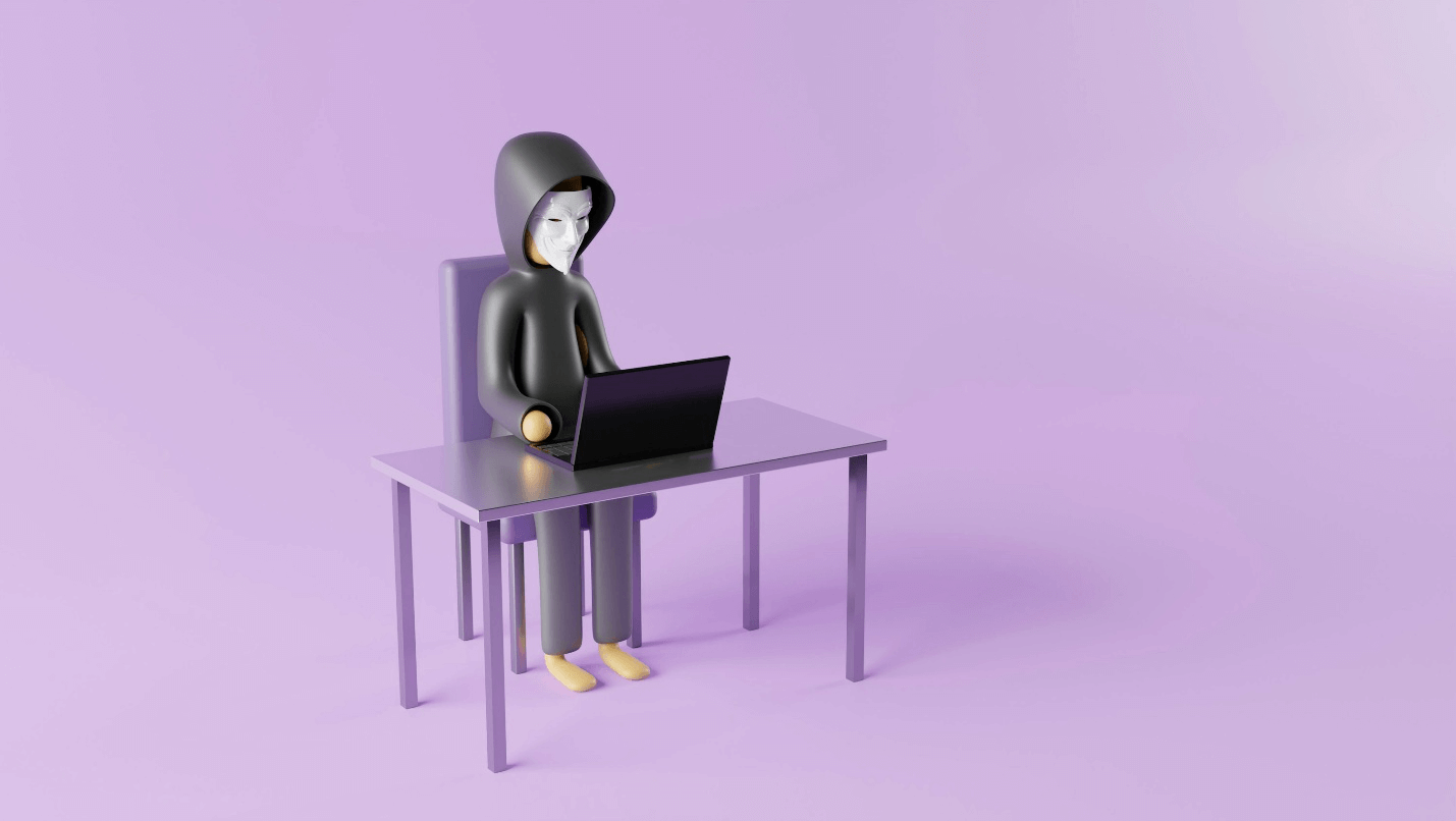 A figure using a laptop wearing a mask and a hood