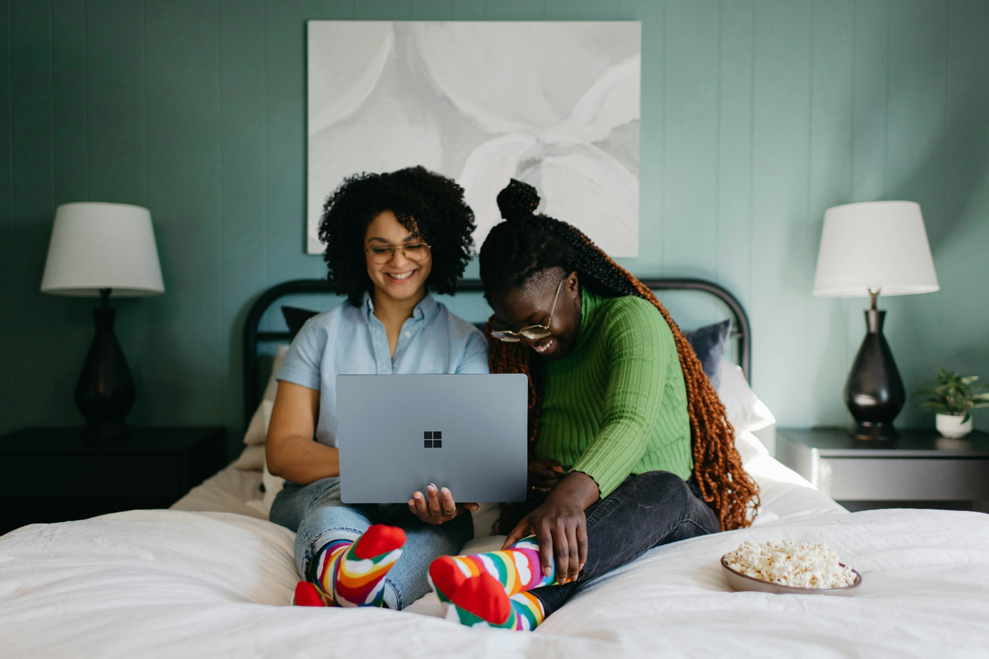 Two women using a laptop in bed