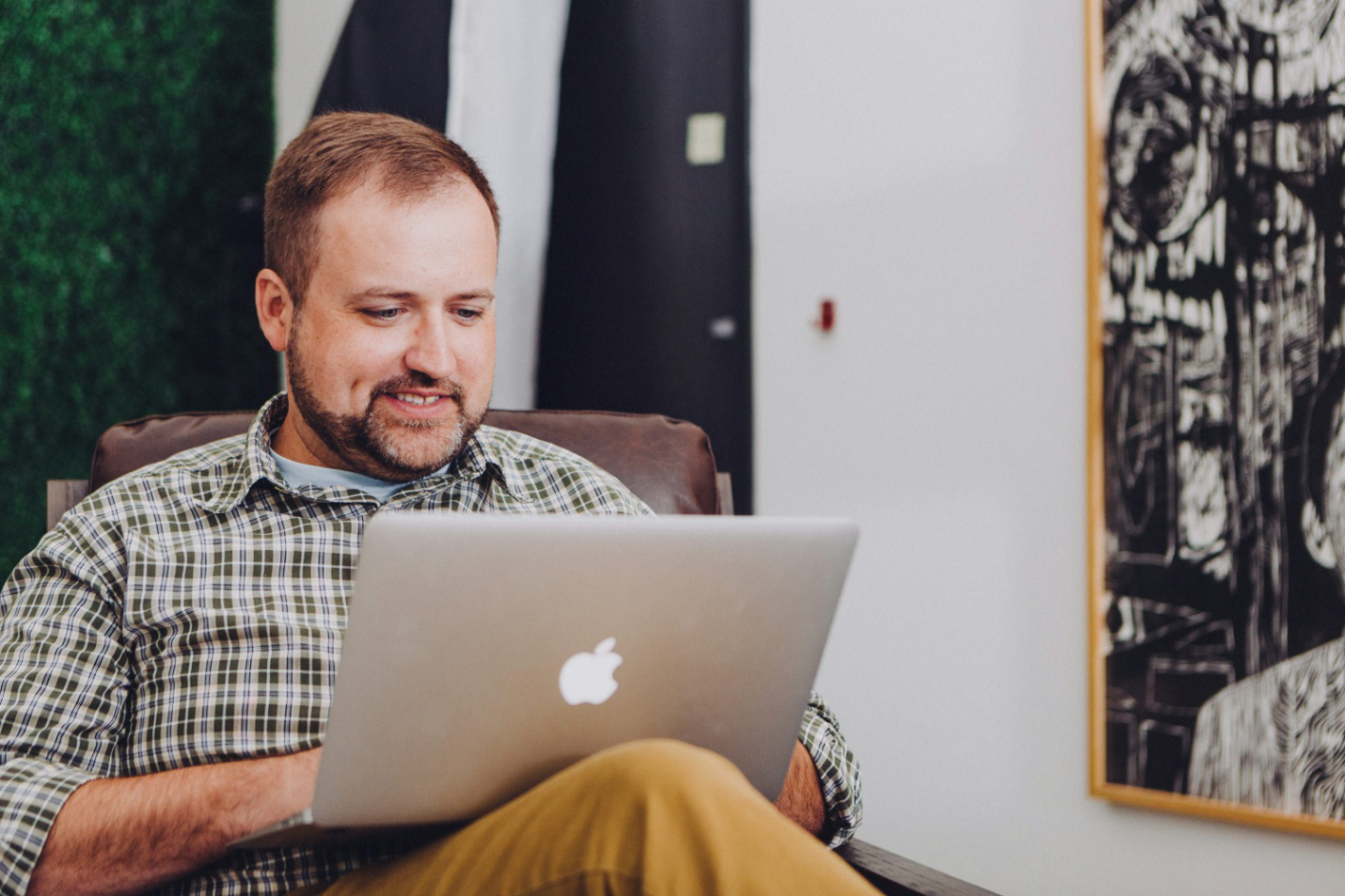 A man smiling at his MacBook