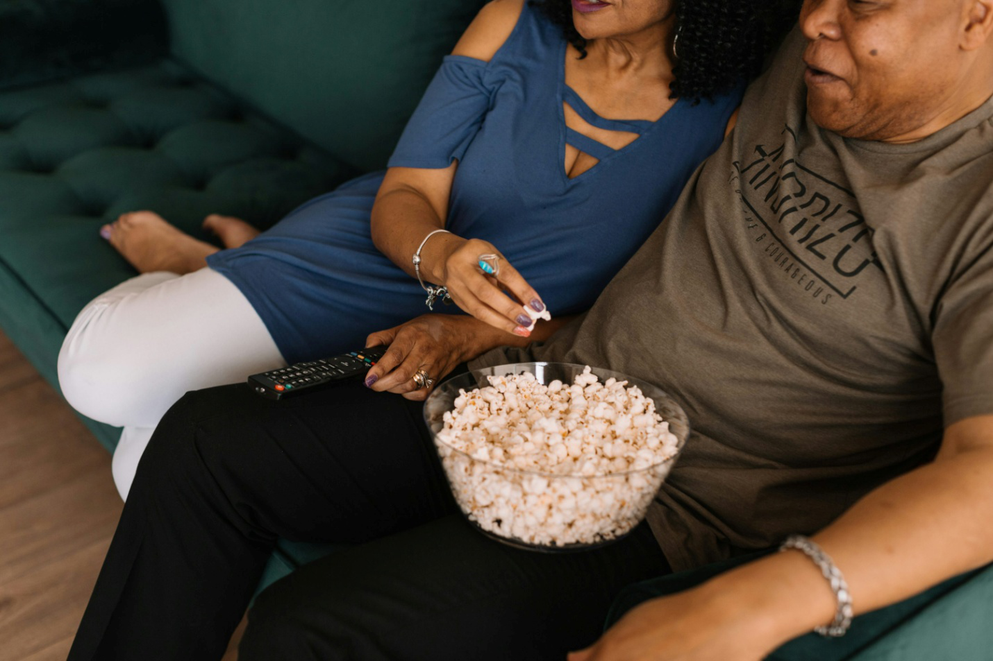 A couple sitting on a couch and eating popcorn