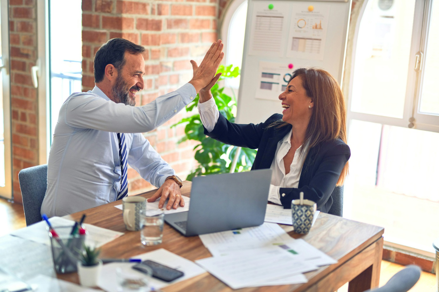 A man and woman in business clothes, high-fiving