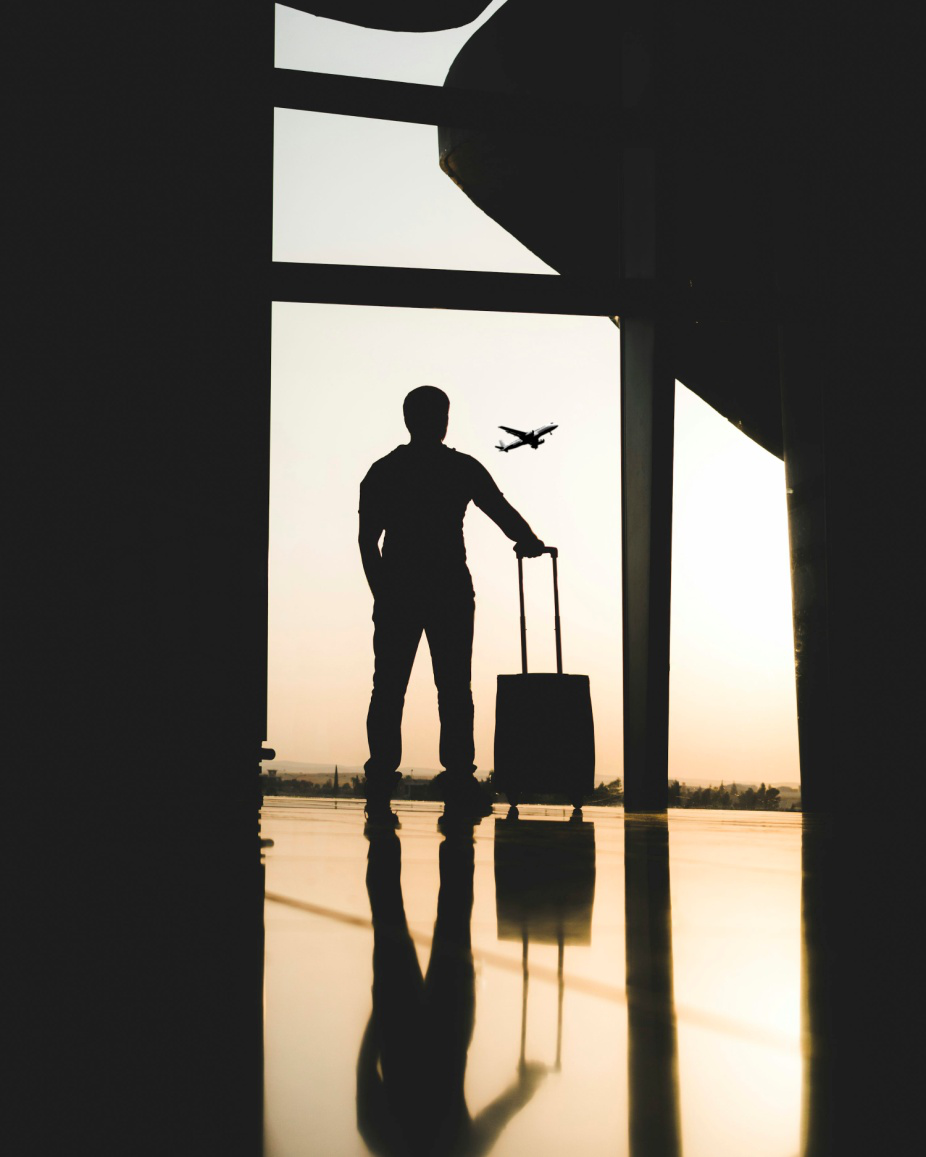 A man holding his luggage and looking at an airplane