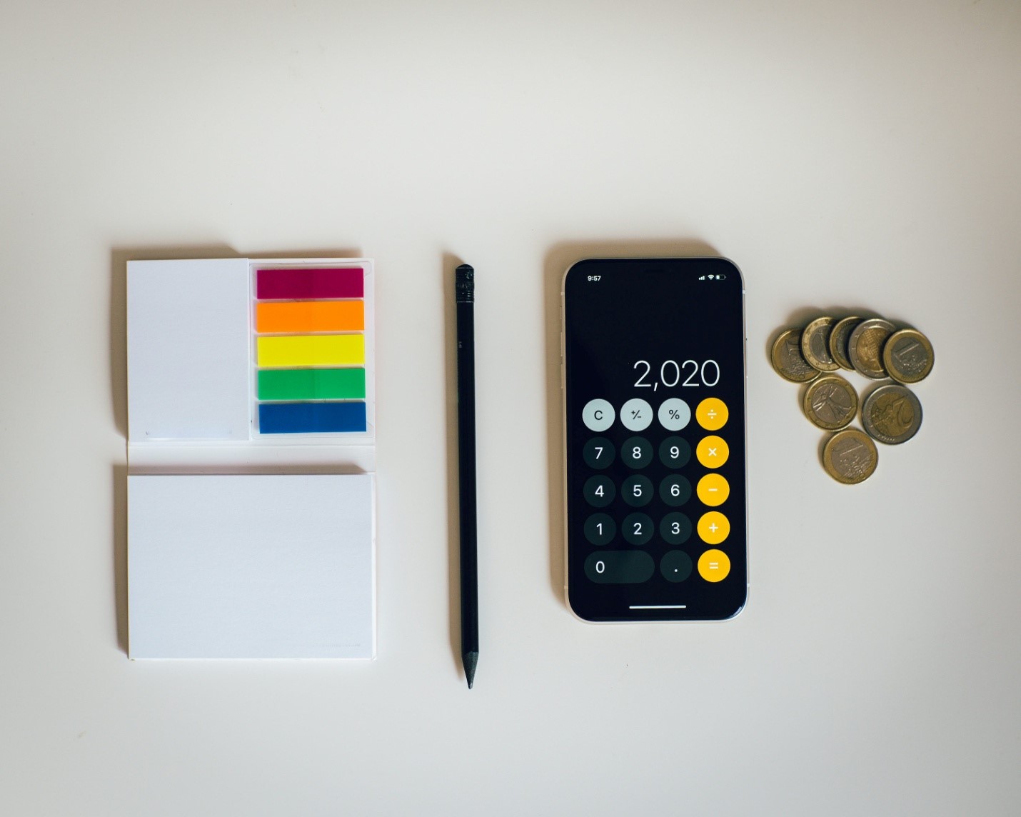 A calculator and sticky notes next to a pile of coins 